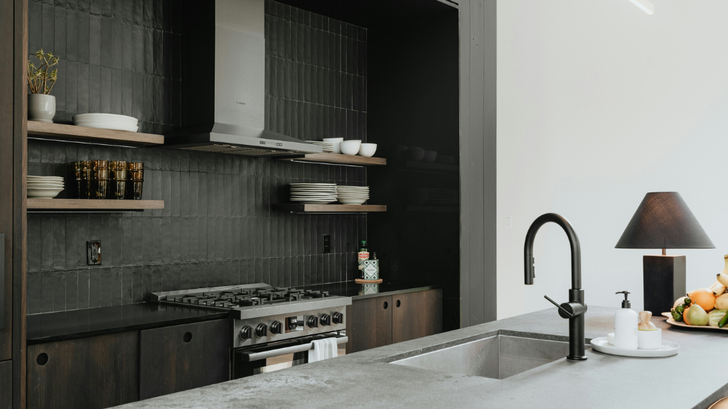 sleek and modern kitchen showing a range and sink and floor to ceiling windows